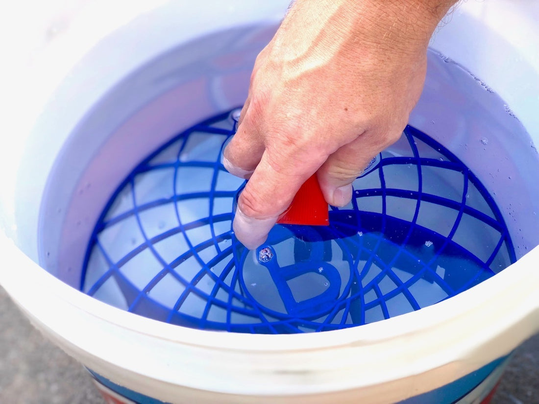 A blue plastic 'Great Barrier Thingy' designed to fit into wash buckets for car cleaning, packaged with product information.